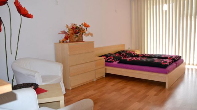 Helles Schlafzimmer in einer Magdeburg-Wohnung mit Blumenmotiv, modernem Bett und Kommode auf Holzboden.