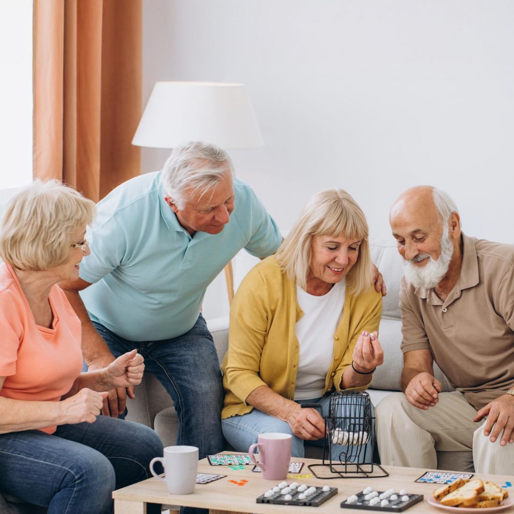 Eine Gruppe älterer Menschen spielt Bingo in einer gemütlichen Wohnung in Magdeburg.