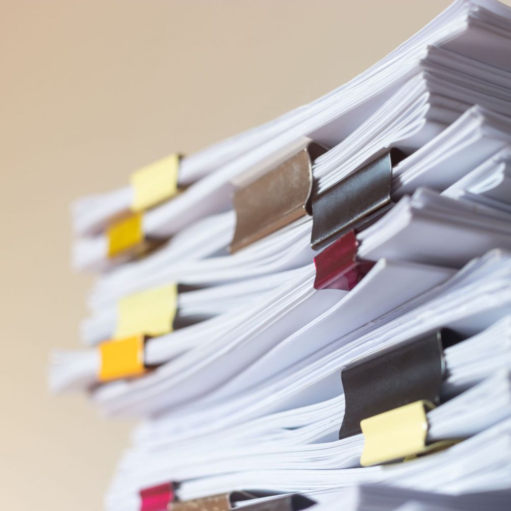 Stapel von Dokumenten mit bunten Büroklammern symbolisieren den Papierkram beim Mieten einer Wohnung in Magdeburg.